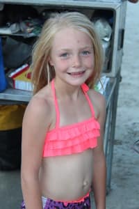 a little girl in a pink bathing suit smiles in the river kitchen on a hells canyon rafting trip