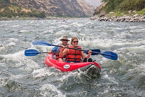 2 people have fun kayaking down the snake river on a rafting trip