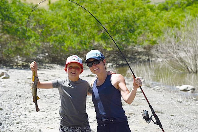 A mom and son posing with a fish on the line during a rafting trip in Hells Canyon.
