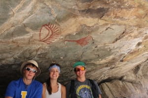 2 red pictographs on rock are above 3 people smiling on a 3 day hells canyon rafting vacation