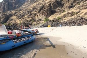 A raft is tied to a sandy beach at a river camp in Hells Canyon during a rafting trip