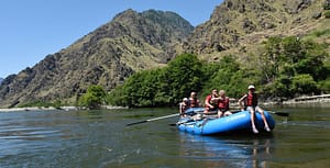 4 kids sit in a raft waiting to get splashed by a rapid in Hells Canyon