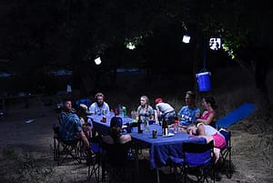 a river dinner table at night under solar lanterns. a family chats before bed on a rafting trip in oregon