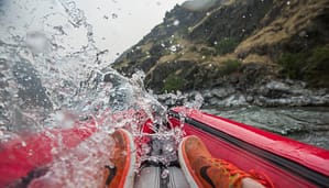 an inflatable kayaker gets splashed in a rapid on the Snake River on a Hells Canyon Rafting Trip
