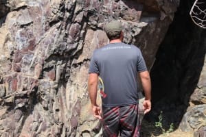 a guide searching for pictographs along the dark lava rocks of hells canyon during a rafting trip
