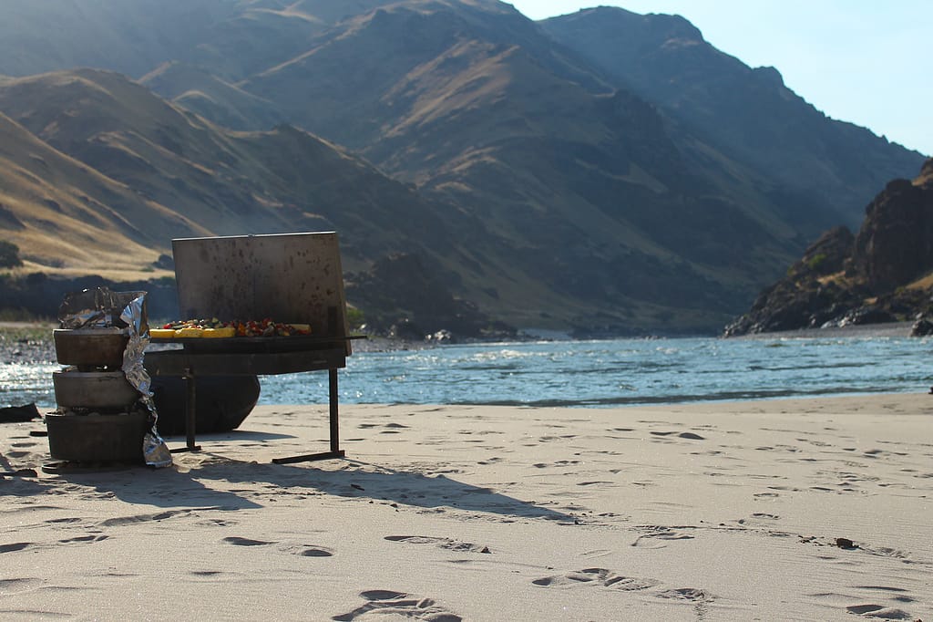 Grilling meat and veggies and dutch oven baking on a sandy river side beach in Hells Canyon on the Snake River
