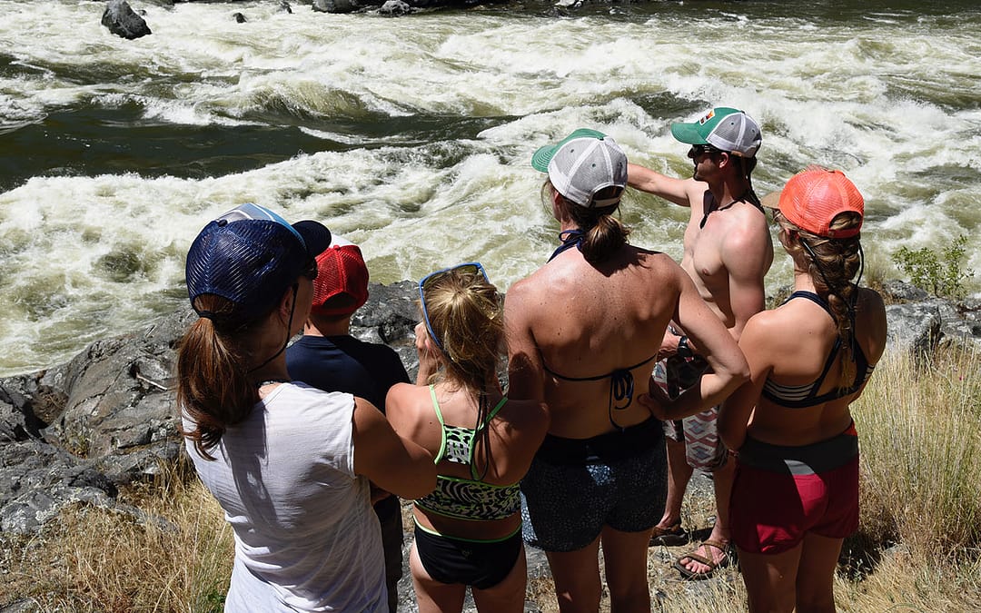 A guide points to a big rapid in Hells Canyon while a group listens