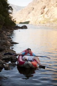 on a hells canyon whitewater river trip, a man is taking a little nap in his kayak