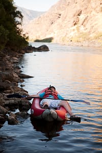 a man takes a little nap in a inflatable kayak during a multi day rafting trip in hells canyon