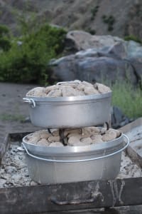 2 dutch ovens topped with charcoal baking bread and chocolate cake for a 4 day hells canyon rafting trip