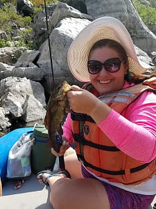 a woman shows off her fish in hells canyon while on a mulitday rafting trip