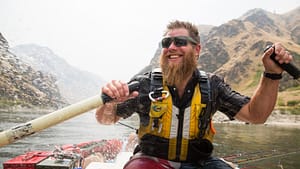 a hells canyon guide smiles while rafting a boat through hells canyon