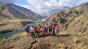 a gorup stand on a ledge in front of the snake river on a hells canyon rafting trip