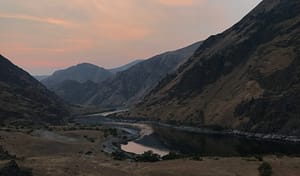 the last of the sun sets in Hells Canyon leaving a pink smoky sky and its reflection in the Snake River