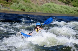 a kayaker all in blue except for her white sunglasses, paddles through some whitewater on a 3 day hells canyon rafting trip