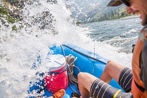 A guy laughs in enjoyment while his boat gets soaked in a rapid in Hells Canyon on a overnight rafting trip