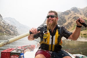 a hells canyon guide smiles while rowing on a whitewater rafting trip in idaho