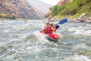 a couple kayaks through whitewater rapids in hells canyon on the snake river