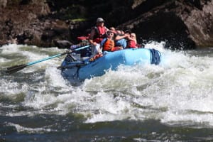 2 boaters lean back in the boat to avoid being splashed while going through a rapid on the snake river