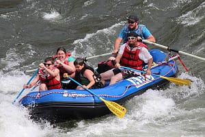 a family paddling and smiling through a rapids during a hells canyon rafting trip