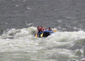 a family digs into the whitewater with their paddles in a rapid on a overnight rafting trip