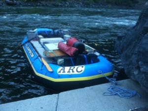 a large blue boat carrying dry bags, coolers and camping gear is waiting for a guide to jump on and begin the best whitewater rafting trips