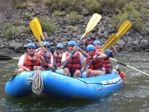 A group outs their Paddles Up while in their raft to celebrate the rapids and the best whitewater rafting trip in Hells Canyon