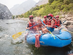 agroup splashes the camera in a paddle boat on the snake river during a whitewater rafting trip