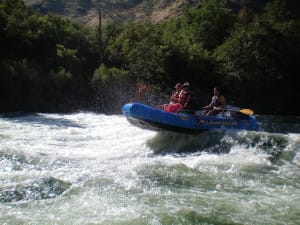 a oar raft is balancing on a rapid, just about to be pushed forward by the wave on the best hells canyon rafting trip
